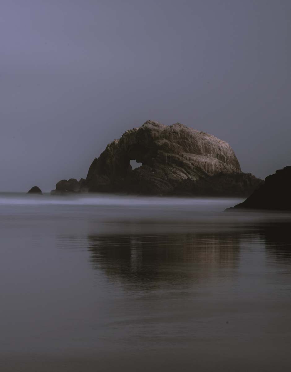 ocean rock formation under gray sky sea